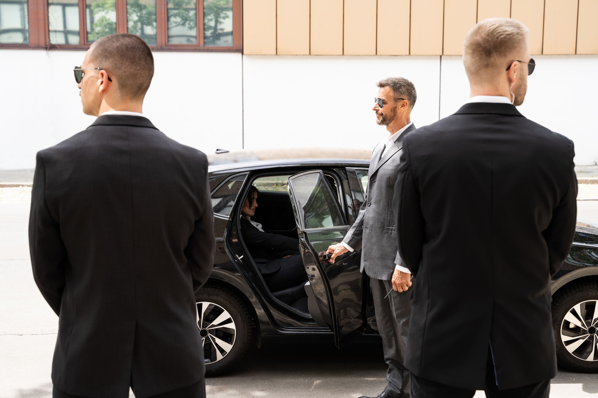 Bodyguards Protecting Businesswoman Opening Car Door